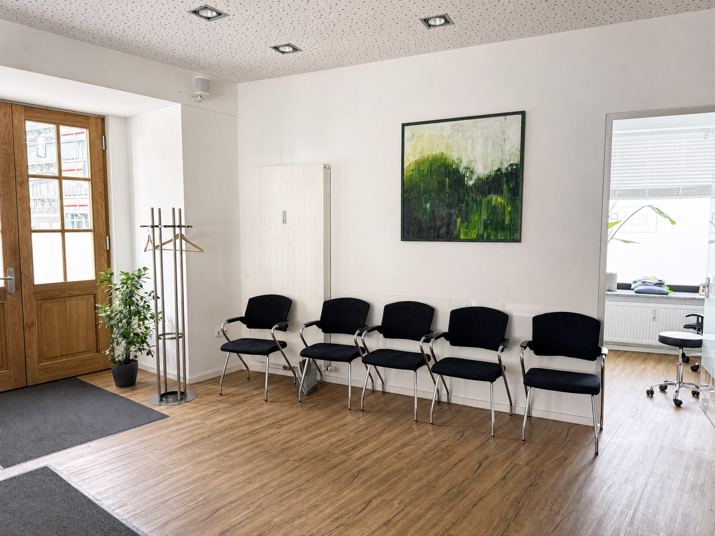 Wartebereich mit Sitzplätzen und Blick in einen Behandlungsraum