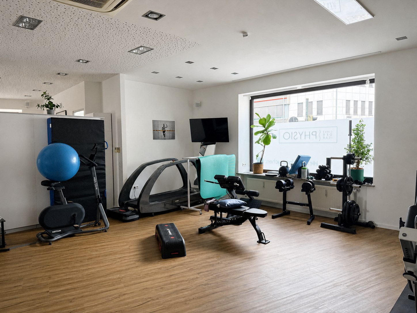 Trainingsraum mit Hanteln, Ergometer und Behandlungsbank