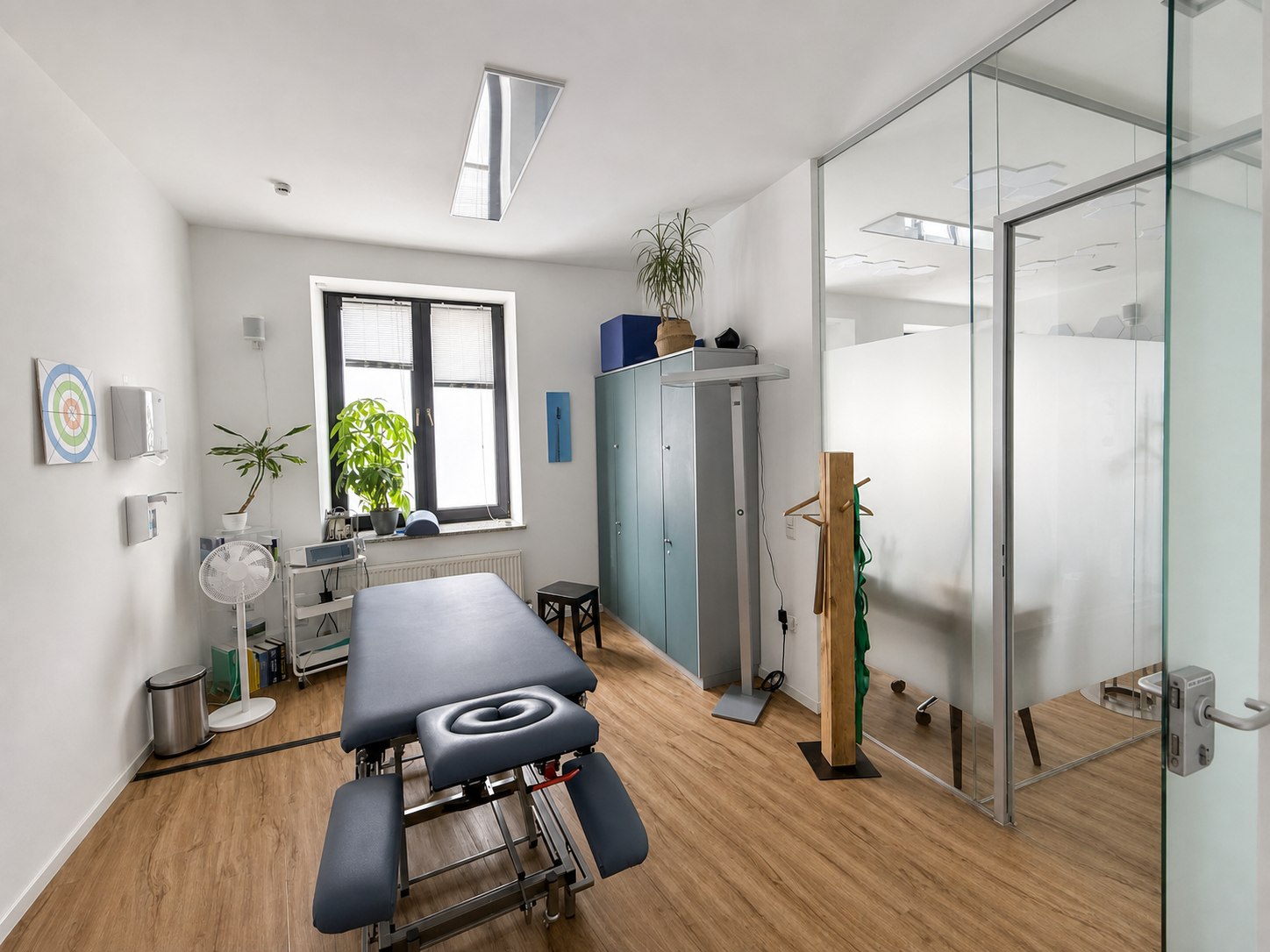Behandlungsraum mit Therapieliege und gläserner Trennwand
