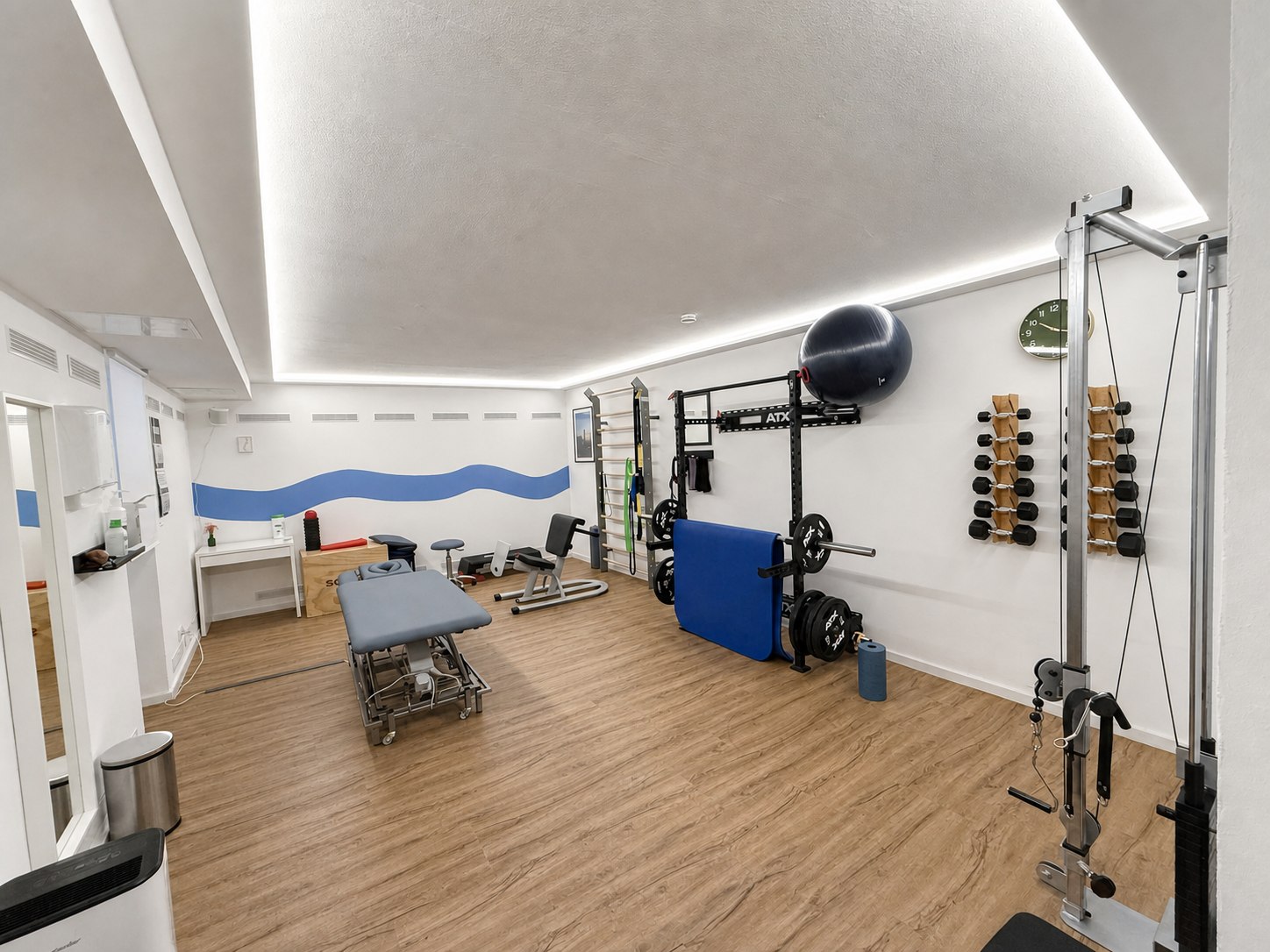 Trainingsraum mit Kraftstation, Hanteln und Therapieliege
